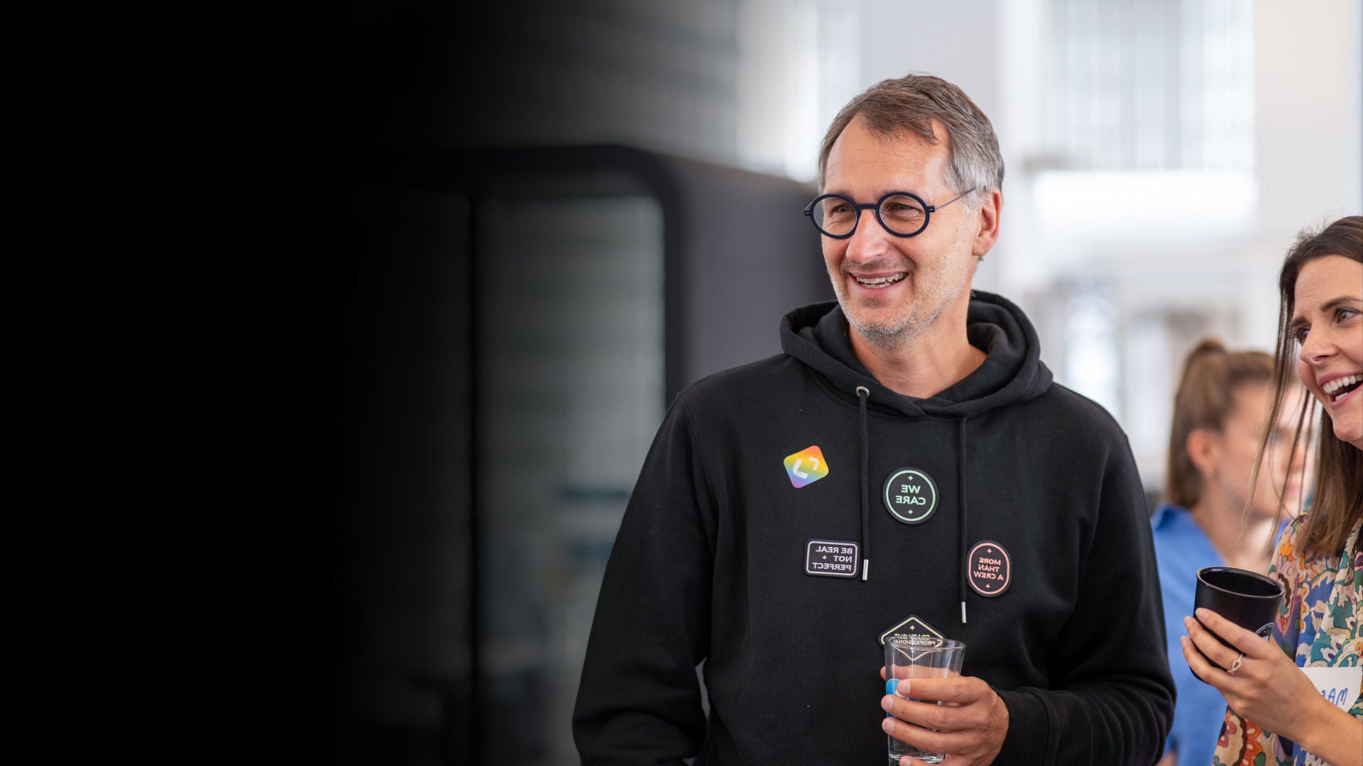 Person in hoodie with glass in hand