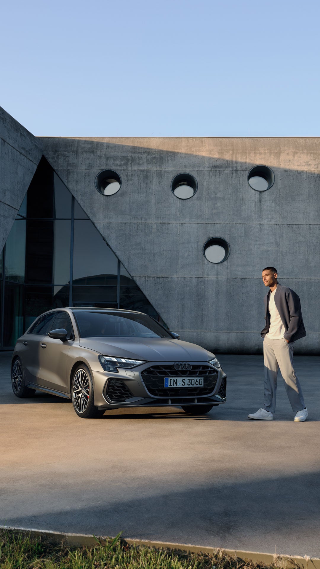 Ein Mann läuft an einem grauen Audi vorbei