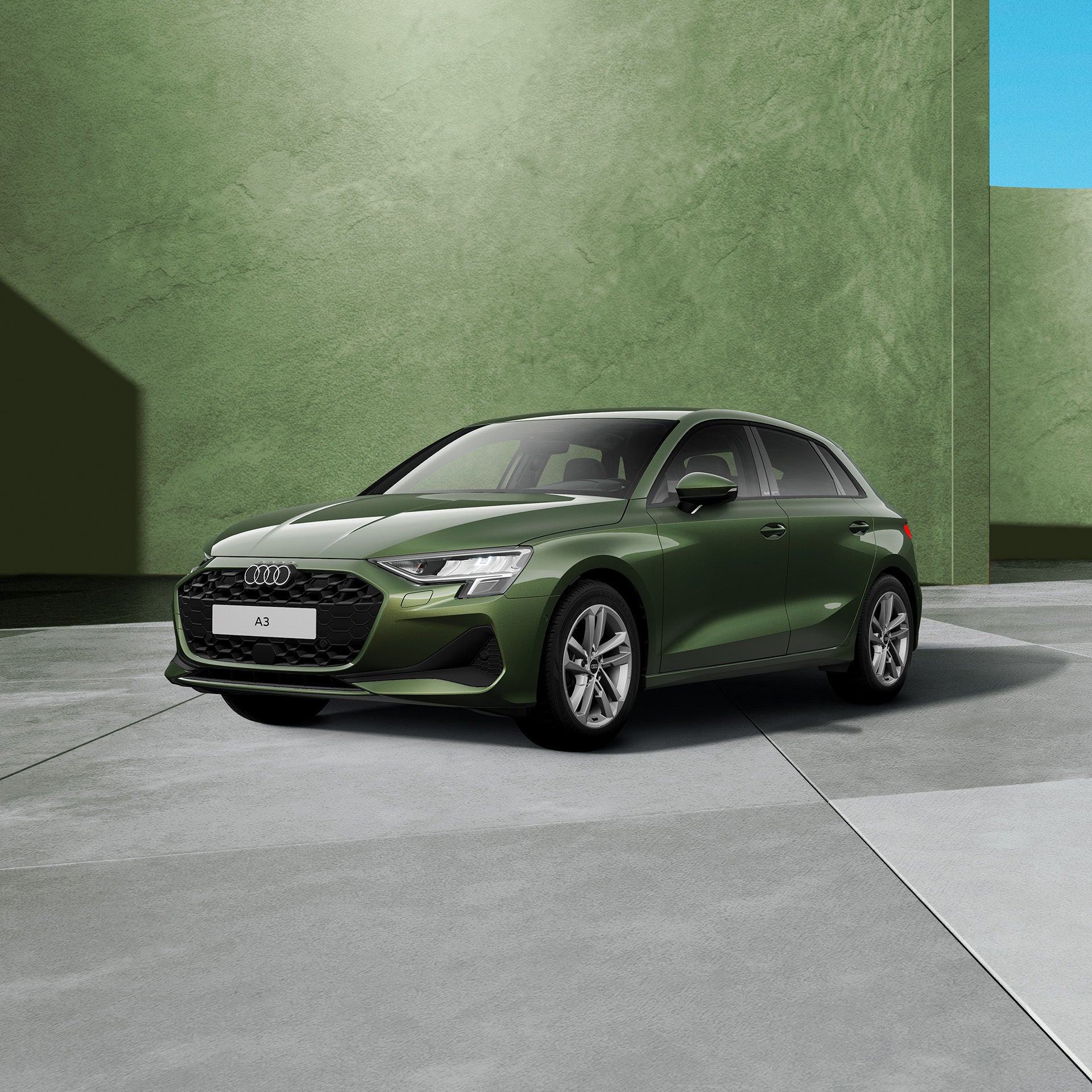 Ein dunkelgrüner, moderner Kombi steht in einem grünen Studio. Das Fahrzeug ist schräg von vorne dargestellt, vor einem grünen, neutralen Hintergrund.