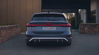 Rear view of Audi S6 Avant e-tron parked in a driveway displaying LED taillights and dual exhausts.