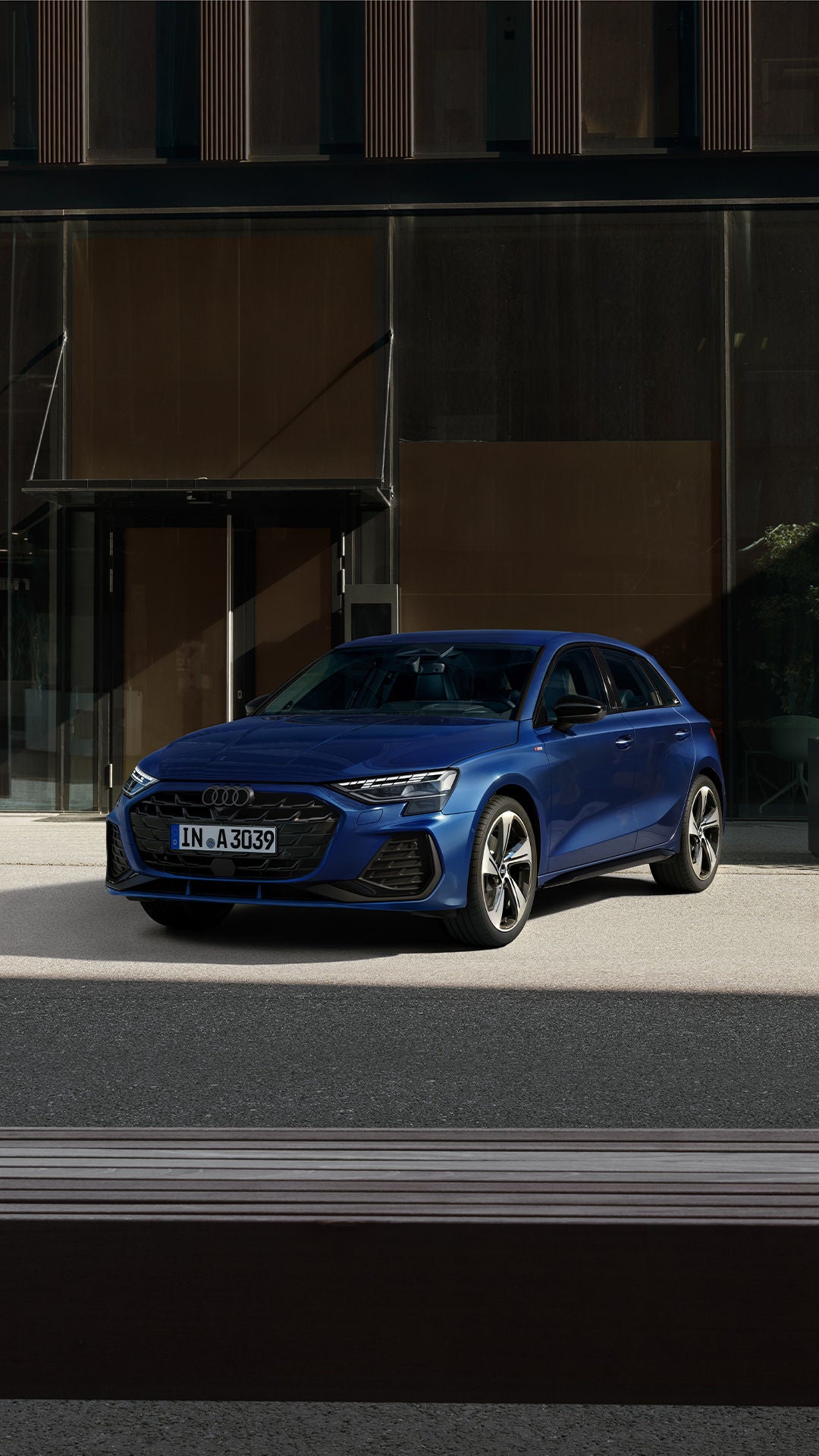 Une Audi Q7 bleue garée devant un immeuble moderne.