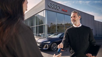 Een Audi medewerker overhandigt de autosleutels, als symbool voor persoonlijk advies en service bij uw Audi ervaring.