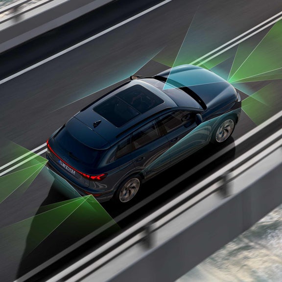 The Q6 SUV e-tron from an angle above. From the rear and front, green and blue vectors divide the areas behind and in front of the vehicle. 