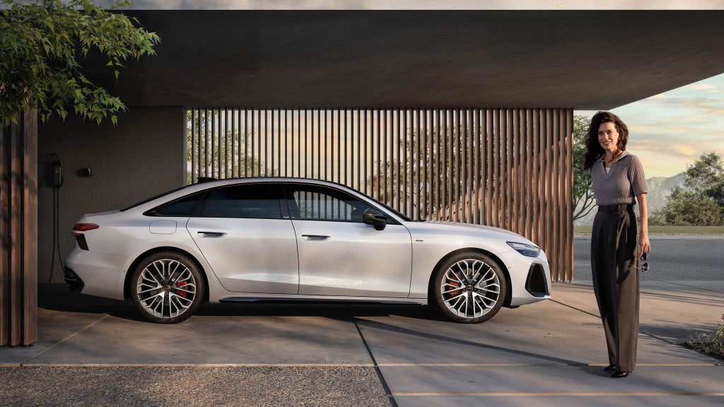  Audi A6 Sedan e-hybrid side view with model standing in front of the Audi A6 Sedan e-hybrid