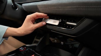 Hand steckt Audi Duftspender in Lüftungsschlitz im Innenraum.