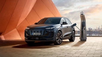 An Audi electric SUV charging at a docking station.