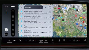 Fahrzeugdisplay mit Google-Zielsuche, Beispielbegriffe wie „Pizza“ oder „Spielplatz“ werden angezeigt.