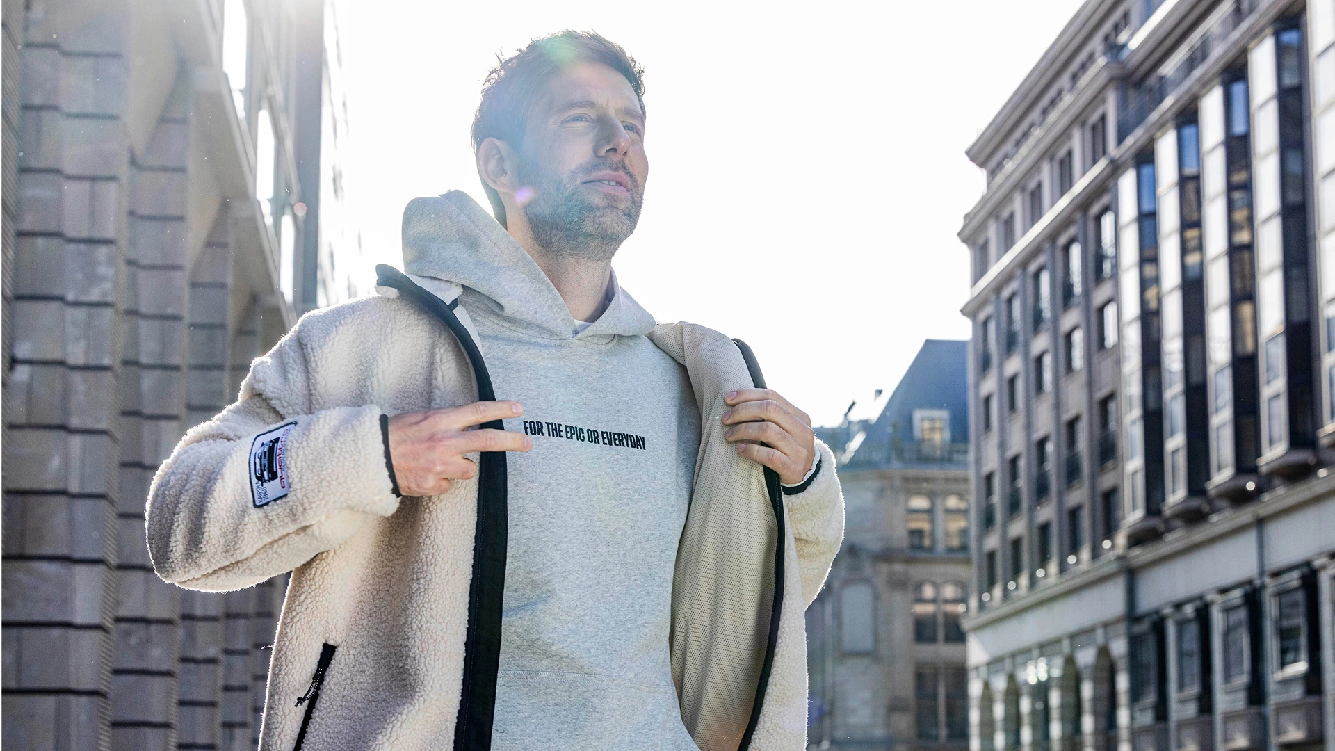 A man wearing a white Audi fleece jacket walking on a busy street. 