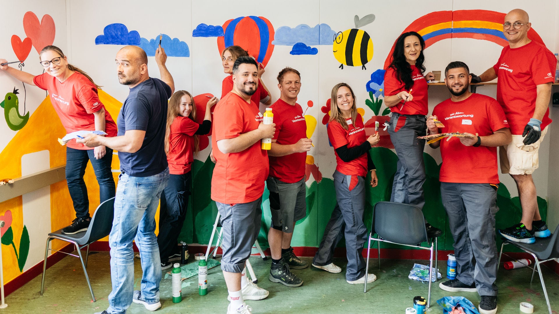 Der Vorsitzende des Gesamtbetriebsrats von Audi, Jörg Schlagbauer, steht mit Arbeitskollegen in einem Raum und bemalt die Wände mit bunten Farben.