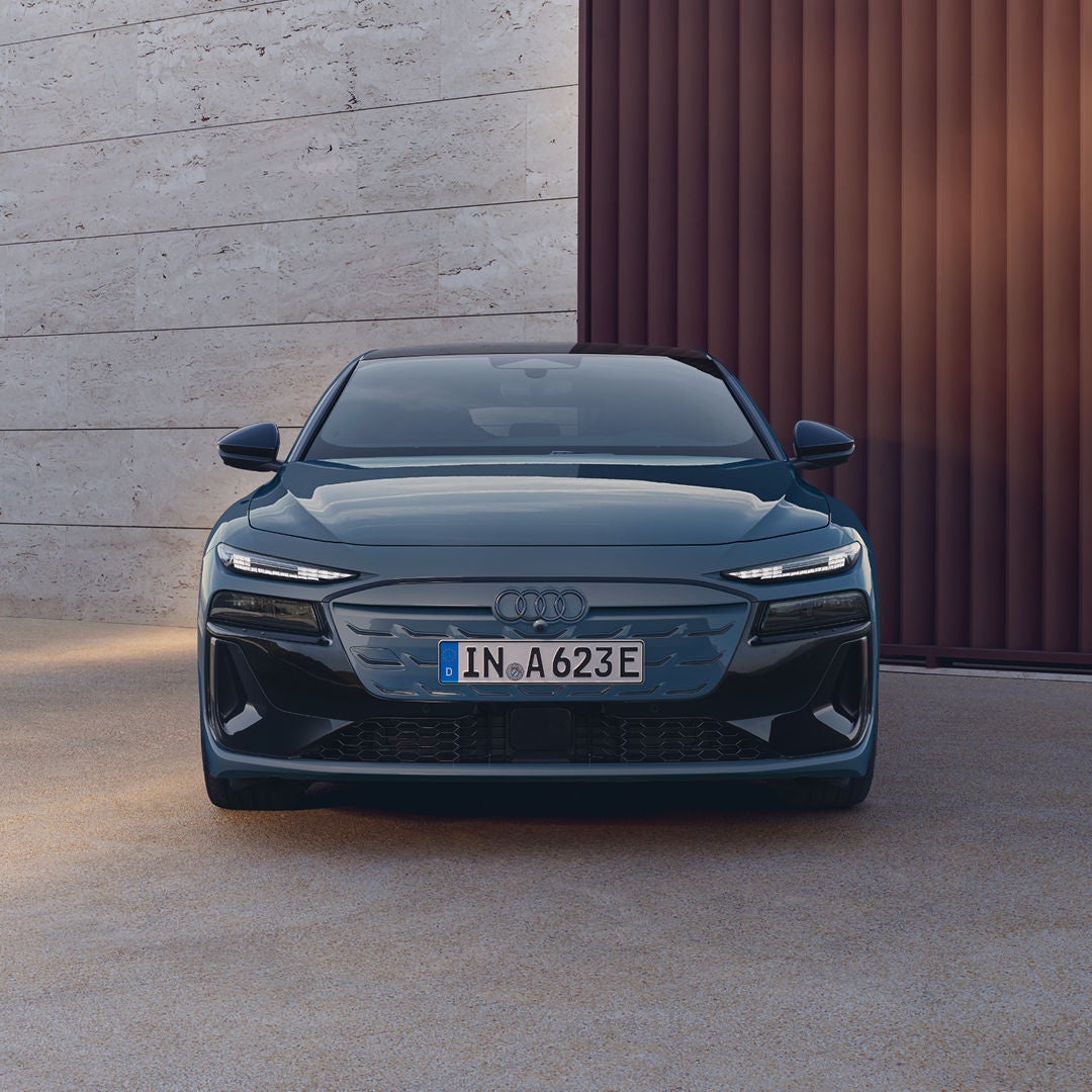 A black Audi vehicle parked beside a modern house