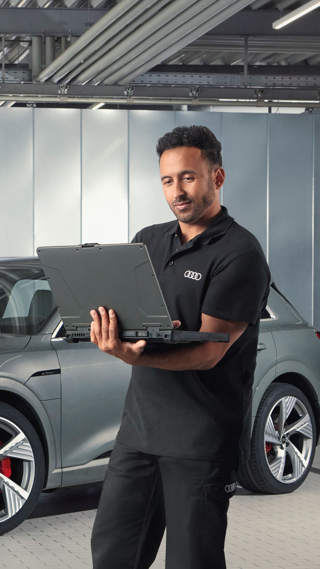 tecnico di officina consulta il computer, dietro di lui un auto Audi