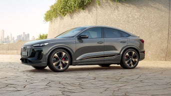 Grey electric SUV charging outdoors with city skyline in the background.