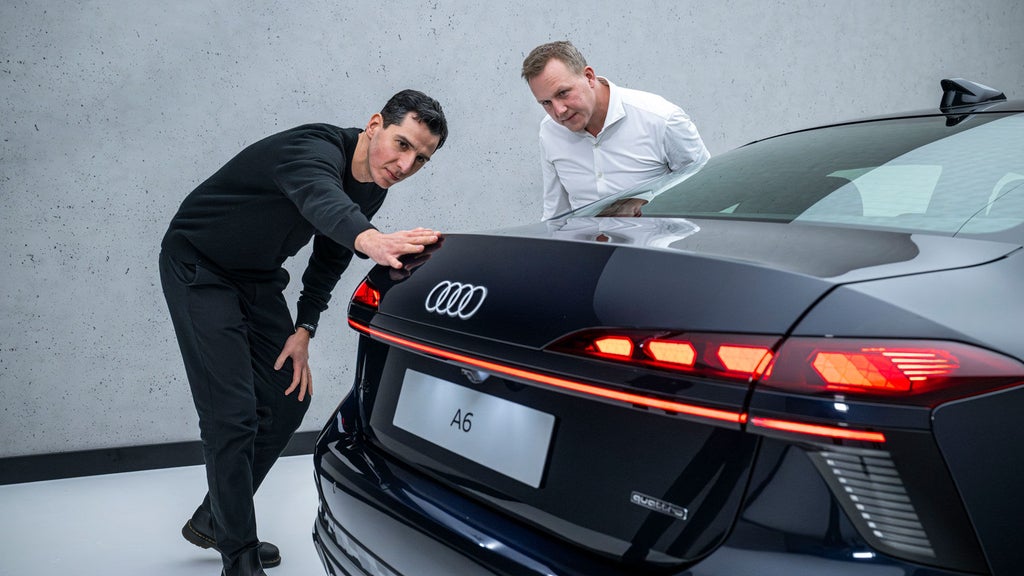 Experten im Gespräch. Designer Francesco d’Amore streicht mit der Hand entlang der Hecklinie des schwarzen Audi A6, neben ihm Aerodynamiker Sebastian Weiper.
