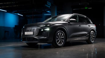 The Q6 e-tron with its sloping rear profile as it drives along a coastal road.