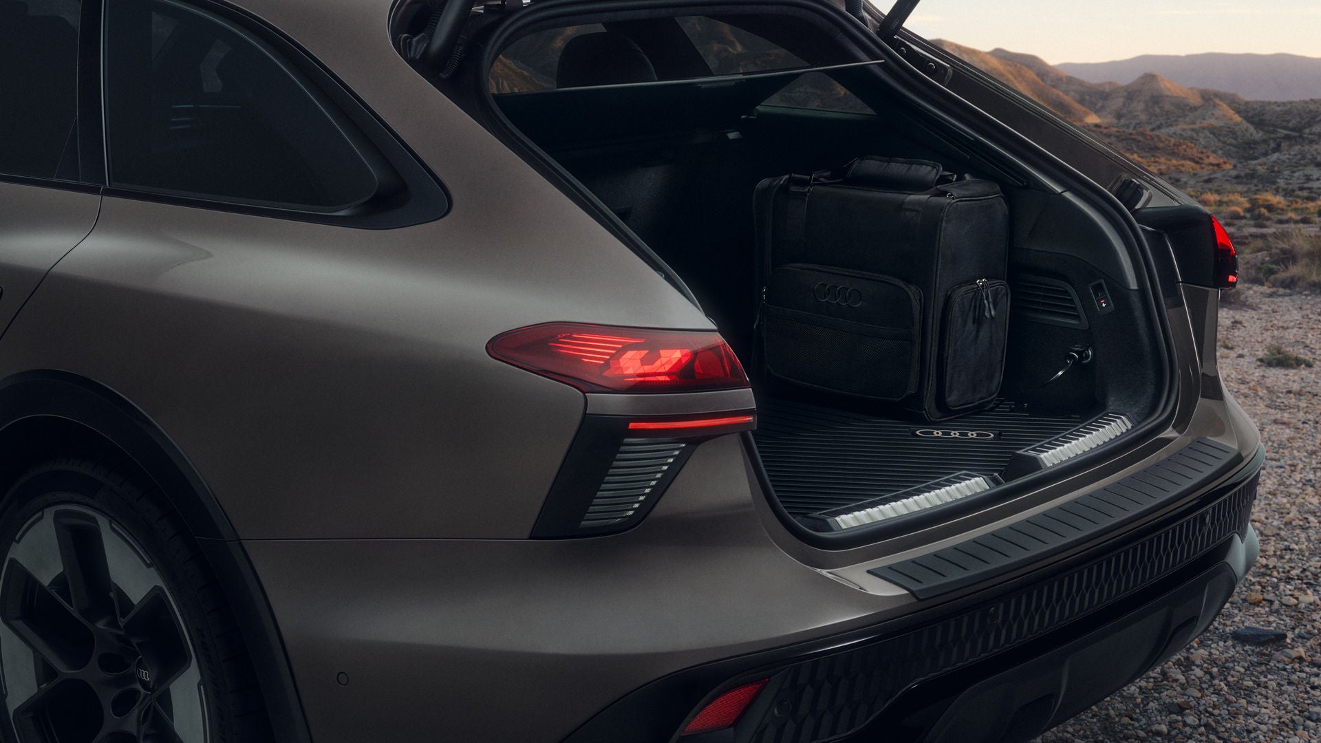 Close-up of the rear of an Audi A6 allroad parked on a gravel road. The 14-liter cooler is sitting in the open trunk.