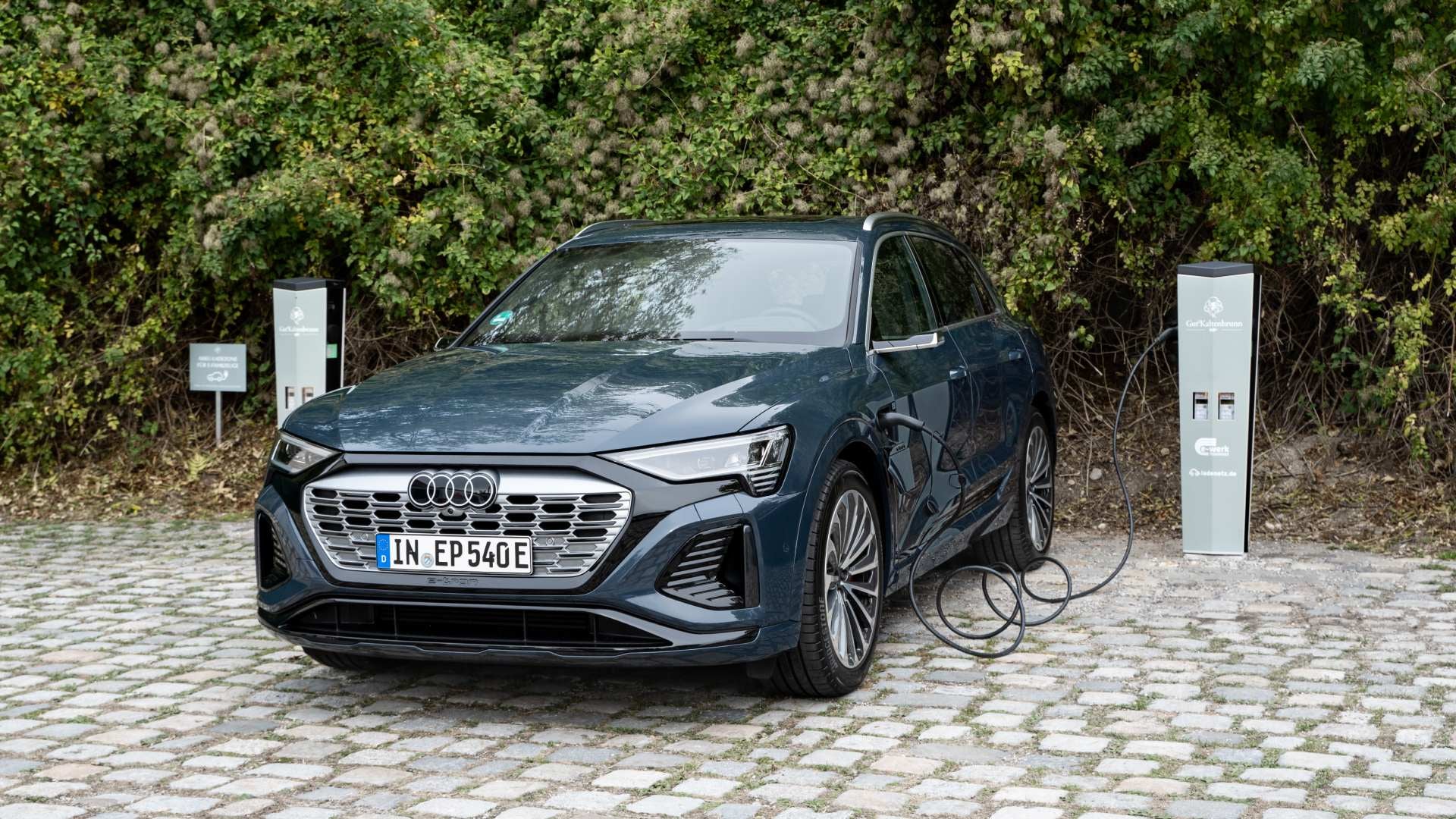 An Audi Q8 e-tron connected to a charging station. 