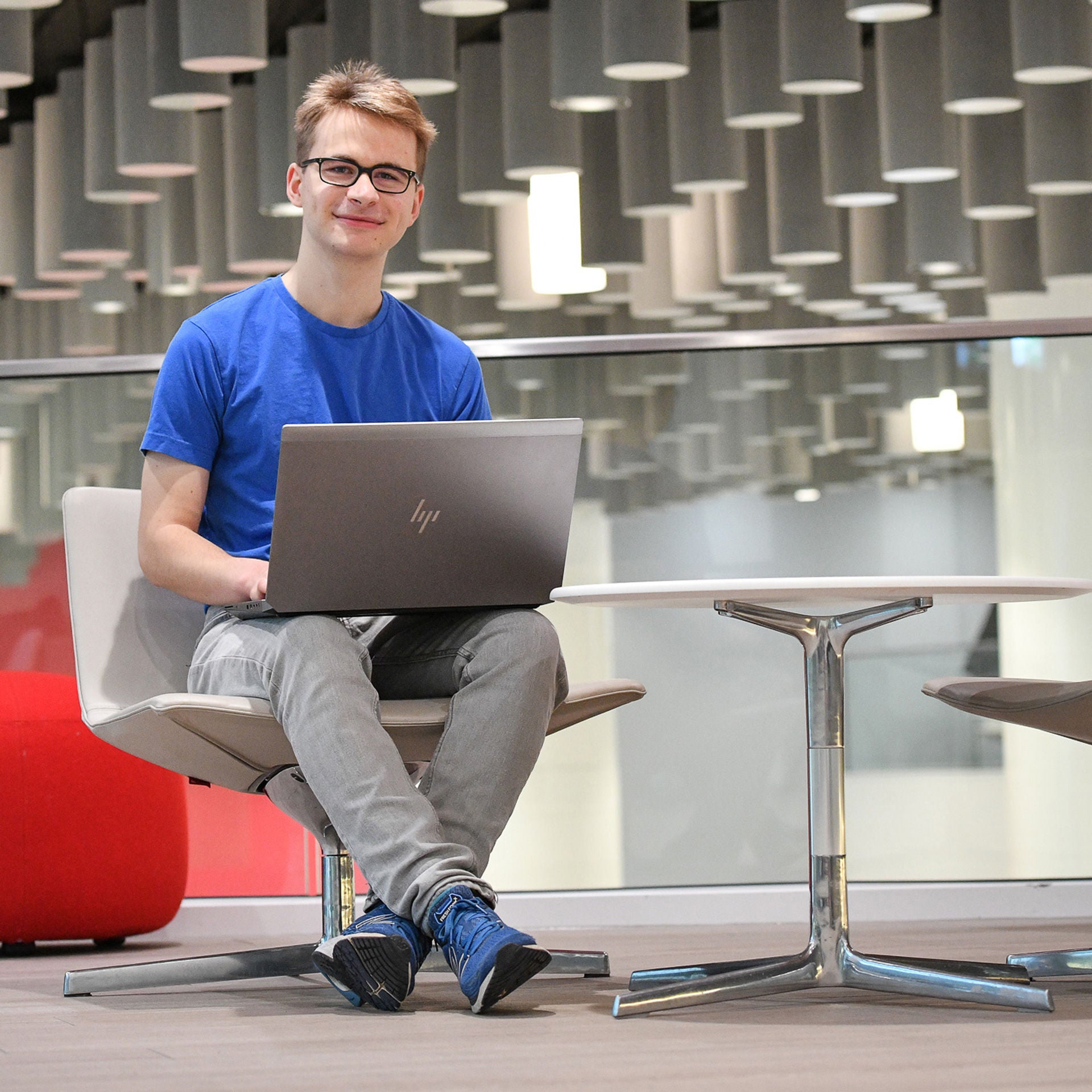 Tim sits at a table in the cafeteria with a laptop