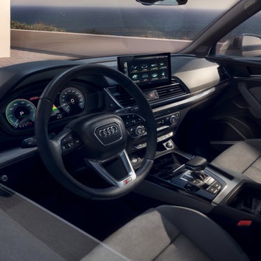 Interior view of an Audi vehicle with steering wheel, dashboard, and infotainment system.
