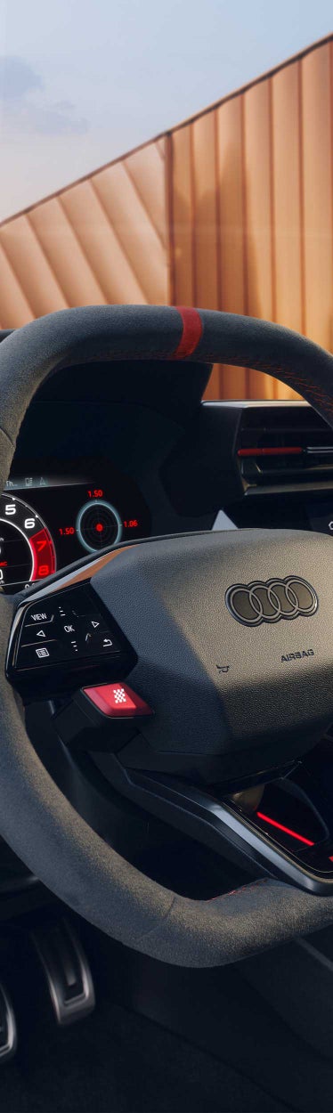 Detailansicht eines Audi-Lenkrads mit roten RS- und Performance-Tasten sowie Alcantara-Bezug mit roter Naht.