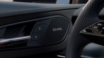 Close-up of Audi Q3 interior door showing Sonos speaker, door handle, lock buttons, and steering wheel detail.