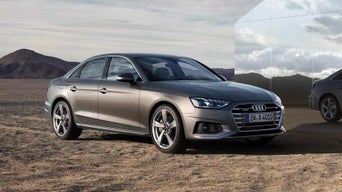 A silver Audi vehicle parked on a desert landscape under a cloudy sky