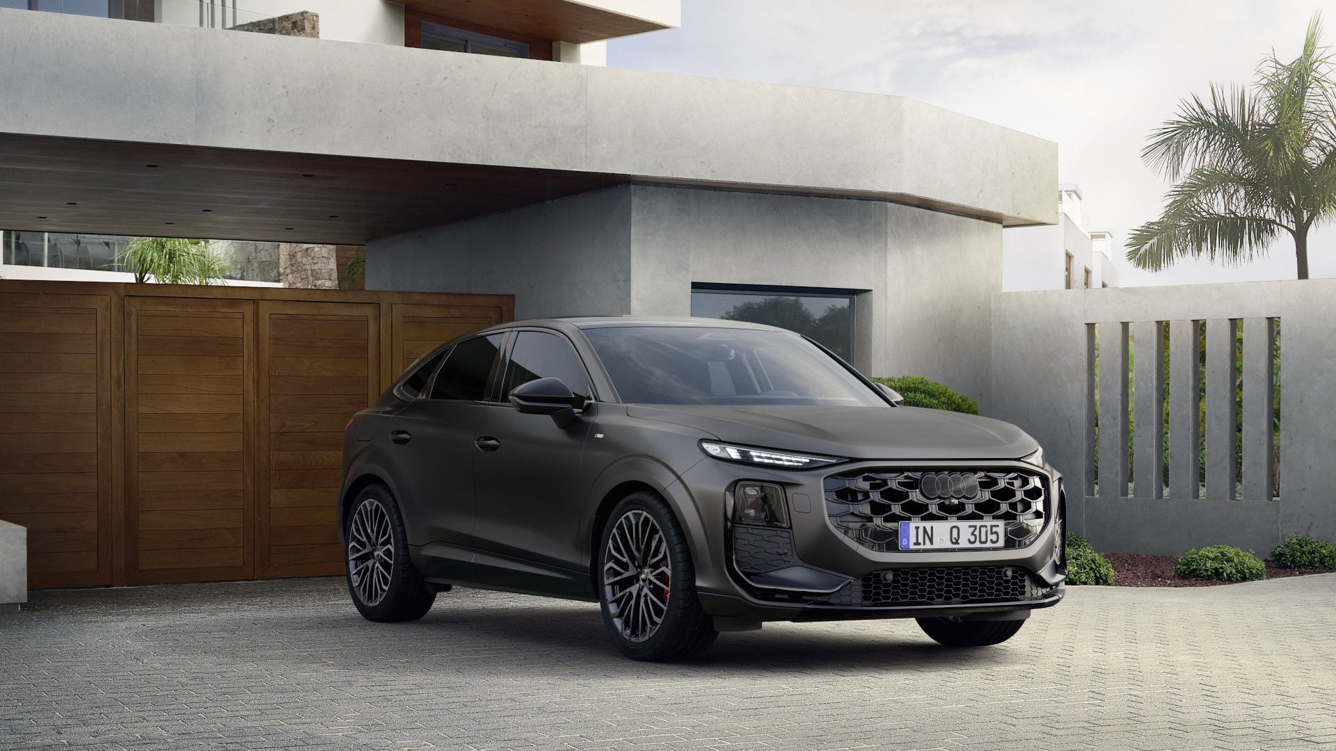 Audi Q3 Sportback staat geparkeerd voor de garagedeur van een modern huis.