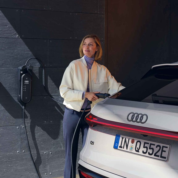 Una donna carica un’Audi Q5 Sportback e-hybrid a casa