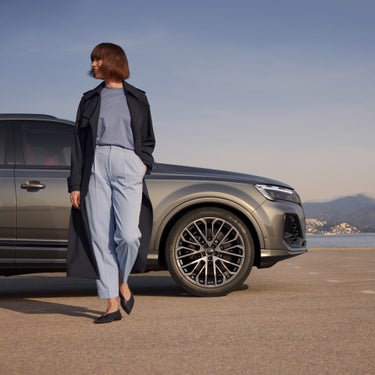 A person standing beside a SUV with a scenic backdrop.