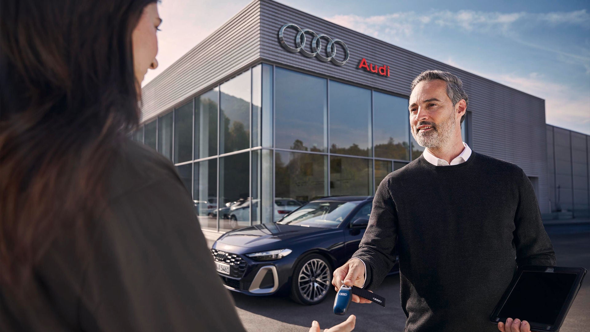 A woman receiving keys for her new Audi at a dealership