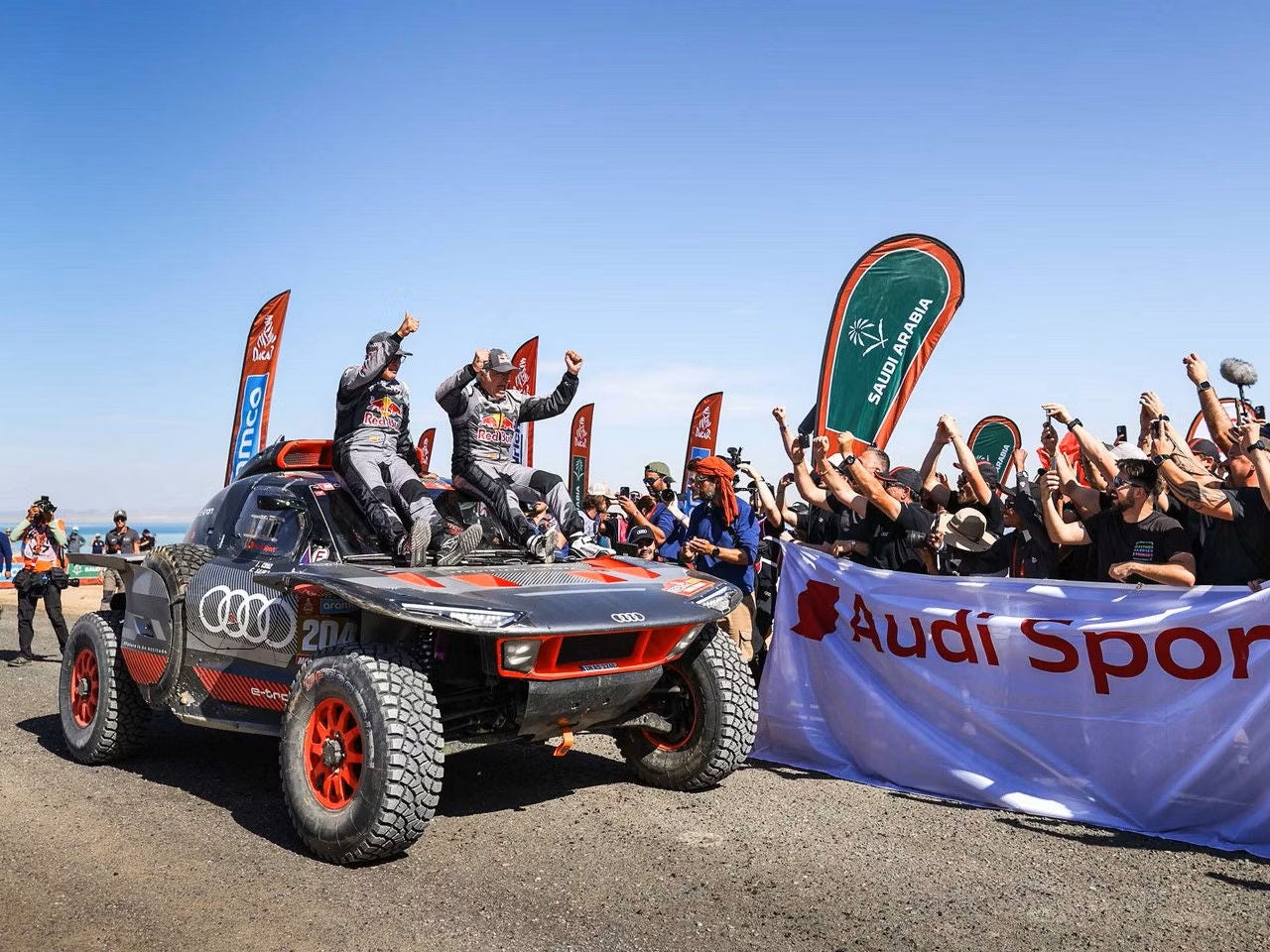 Förare och kartläsare sitter på motorhuven till sin Audi RS Q e-tron och firar segern i Dakar 2024.