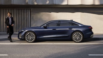 Die A6 Limousine steht im Seitenprofil in einer Parkbucht vor der Fassade eines Gebäudes.