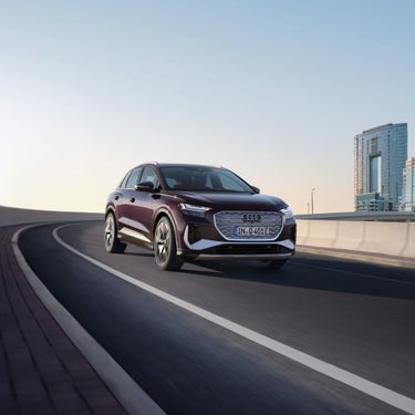 Car driving on a highway with a clear sky and city buildings in the background.