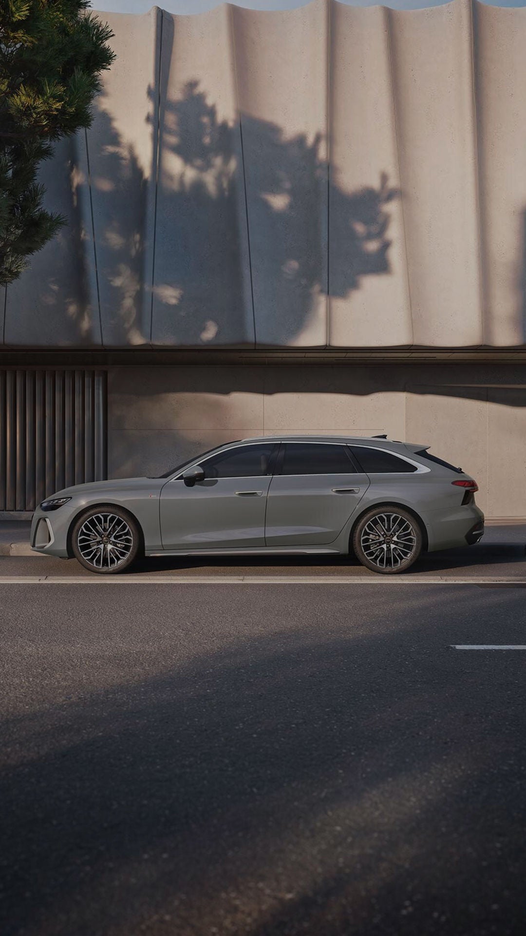 A blue Audi vehicle driving on a mountain road that is curving to the left in the early evening