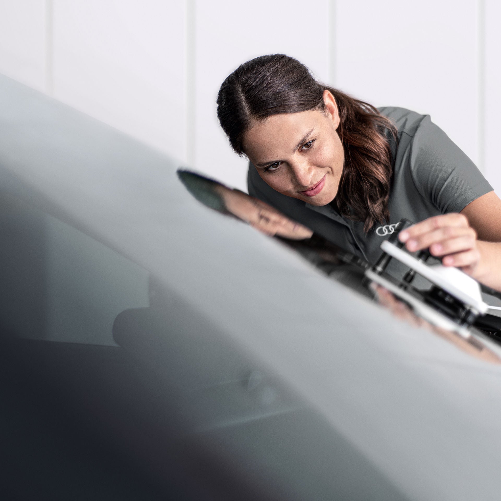 En kvinna som lagar ett stenskott på en framruta i en Audiverkstad