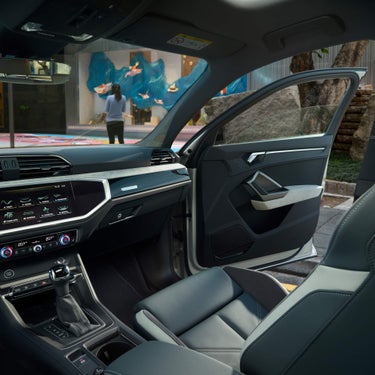 Interior view of Audi Q3 from the drivers side with passenger door left open.