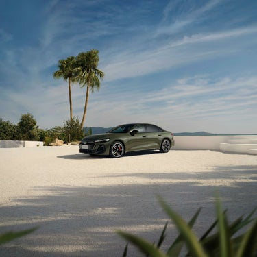 Ein grüner Audi A5L steht auf einer hellen Terrasse mit Palmen, weitem Himmel und Blick auf das Meer.