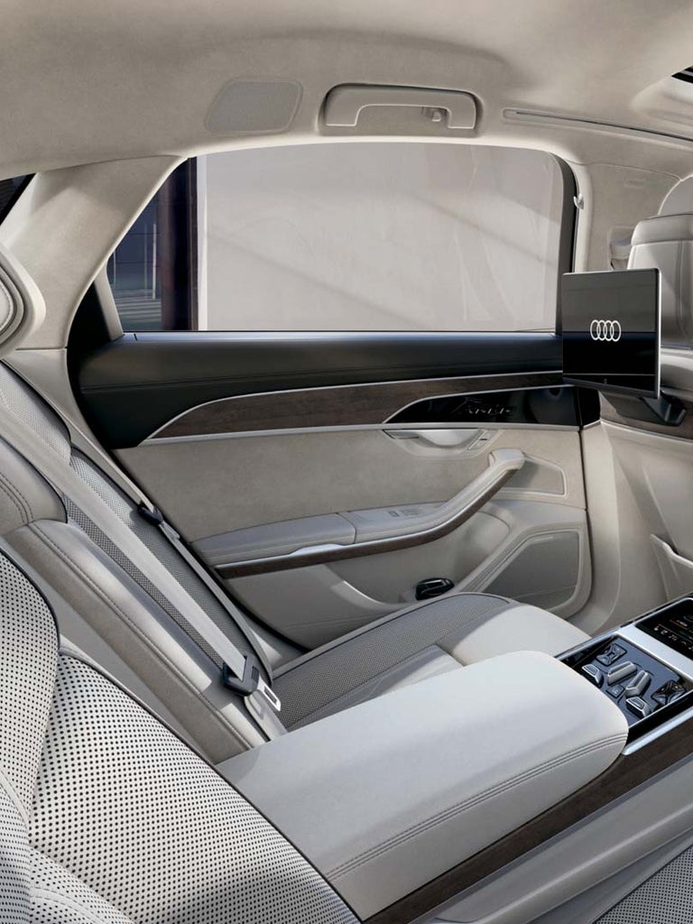 Rücksitzbank eines Audi A8 mit Mittelkonsole und Touch-Bedienelementen in heller Ausstattung.