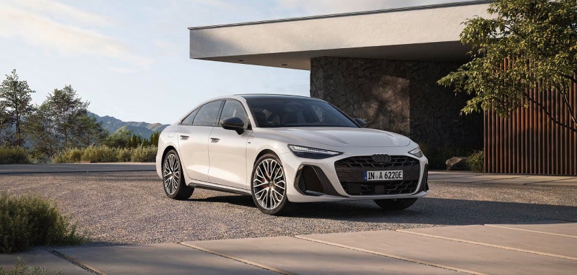 A white Audi parked in front of a modern house