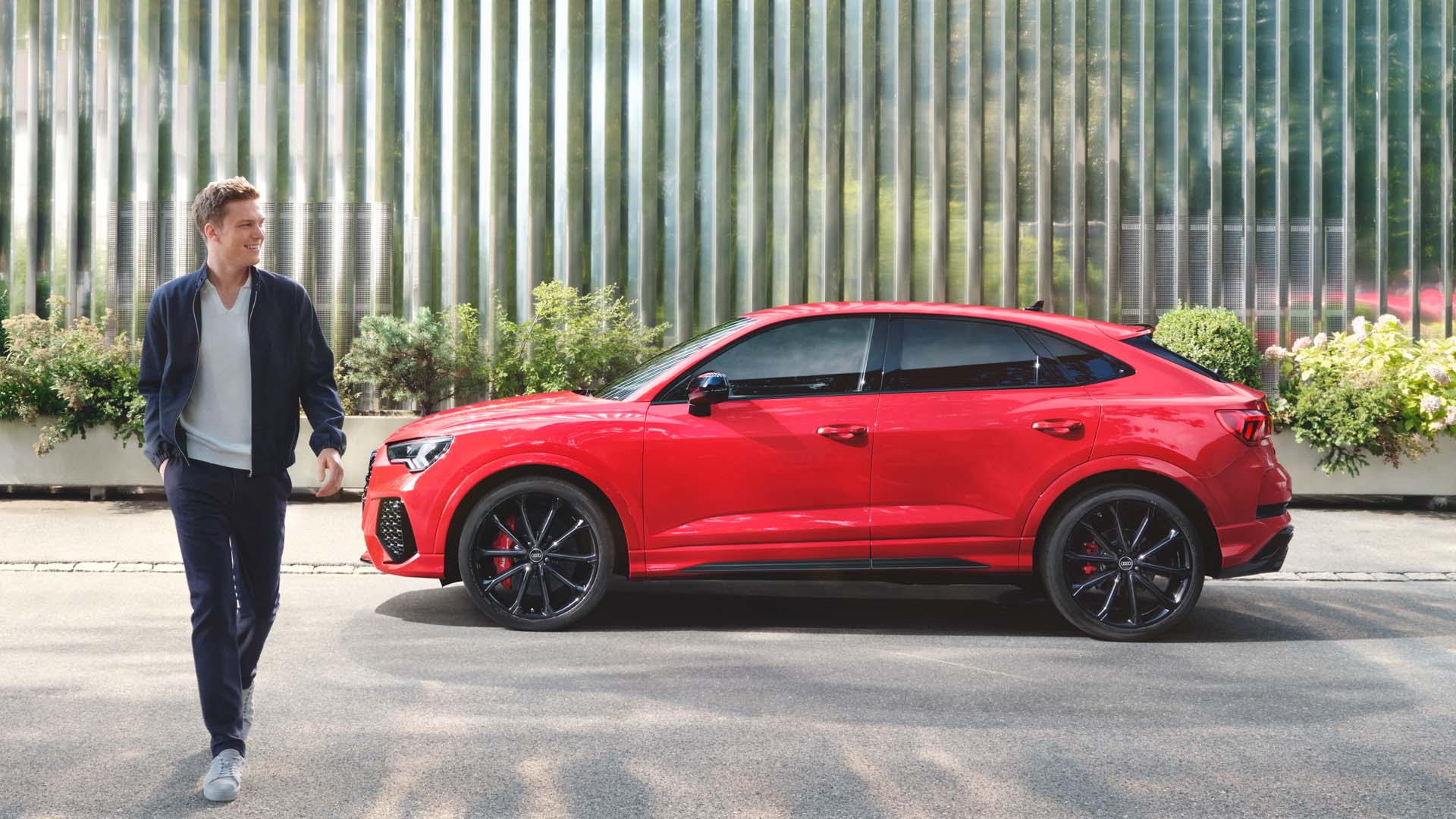 Side view red RS Q3 Sportback with a man in the foreground