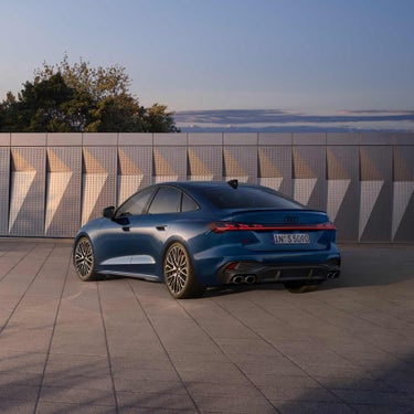 Blaue Audi S5 Limousine steht vor einer Fassade mit geometrischem Muster.