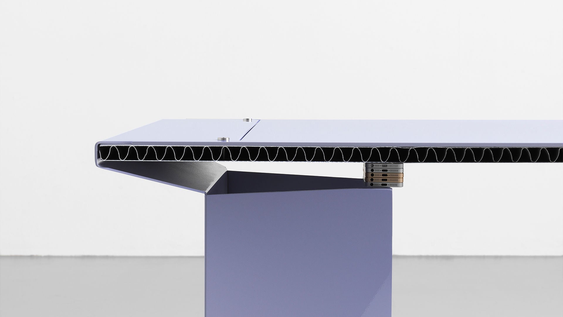 Detailansicht eines modernen, lilafarbenen Tisches mit Wabenkernstruktur und klarer Linienführung vor weißer Wand.