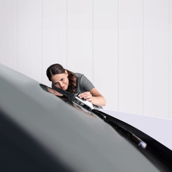 A female Audi Service engineer working the windscreen of an Audi.