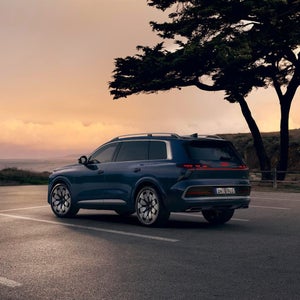 Dunkelblauer Audi Q9 in Dreiviertel-Heckansicht in ruhiger Kulisse und Abendstimmung.