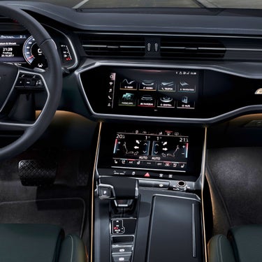 Interior of a car showing a steering wheel, digital dashboard, and center console with touch screens.