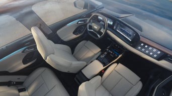 Blick von oben in den Innenraum eines Audi mit zwei vorderen Sitzen, digitalem Cockpit und Mittelkonsole.