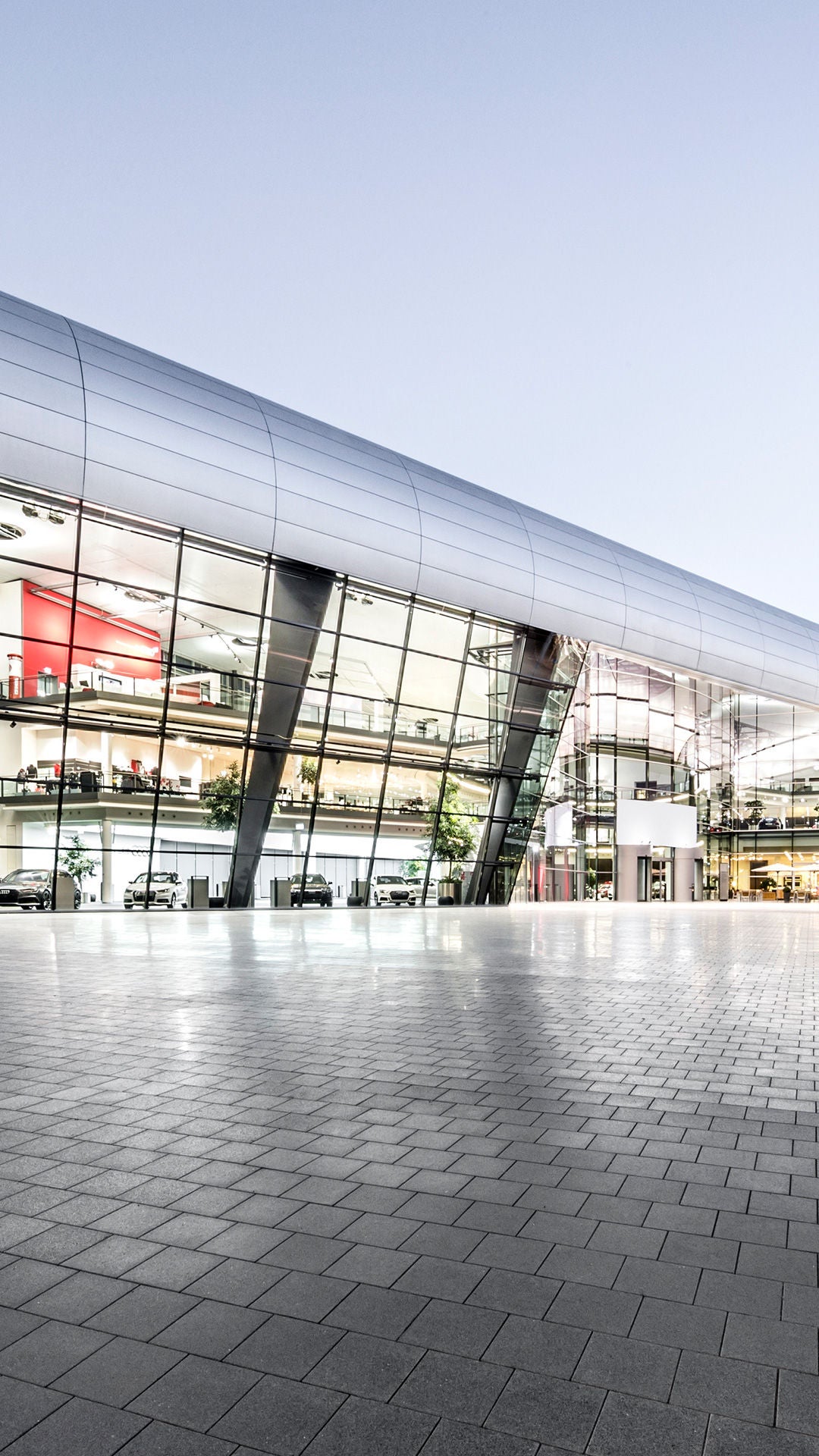 Exterior view of the illuminated Audi Forum Neckarsulm at dusk.