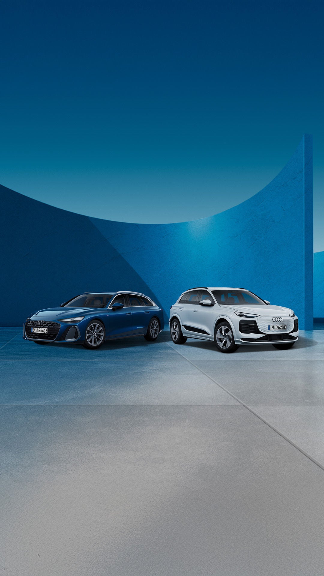 Ein dunkelblauer Audi A6 Avant und ein weißer Audi Q6 e-tron stehen nebeneinander vor einer modernen Kulisse mit geschwungenen blauen Wänden.