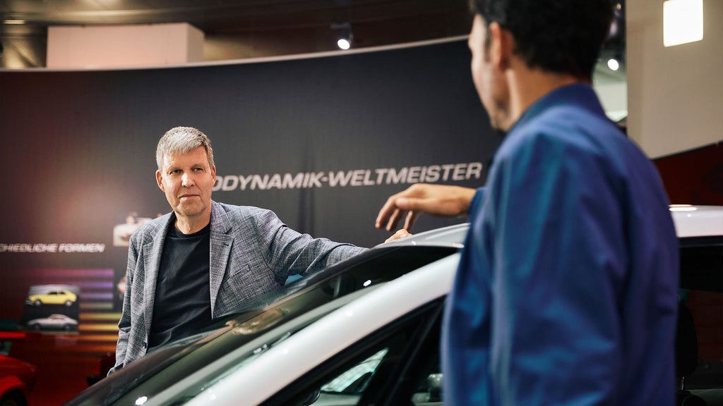 Rüdiger Recknagel und Felix Neureuther schauen sich über Dach eines Audi Modells hinweg an