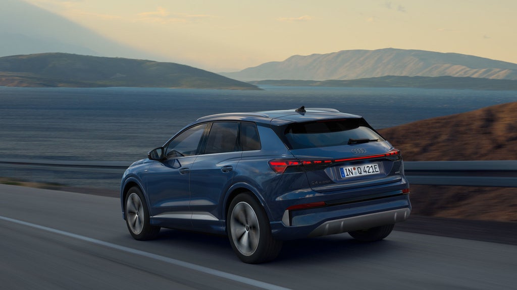 De Q4 e-tron rijdend langs een meer met bergen op de achtergrond