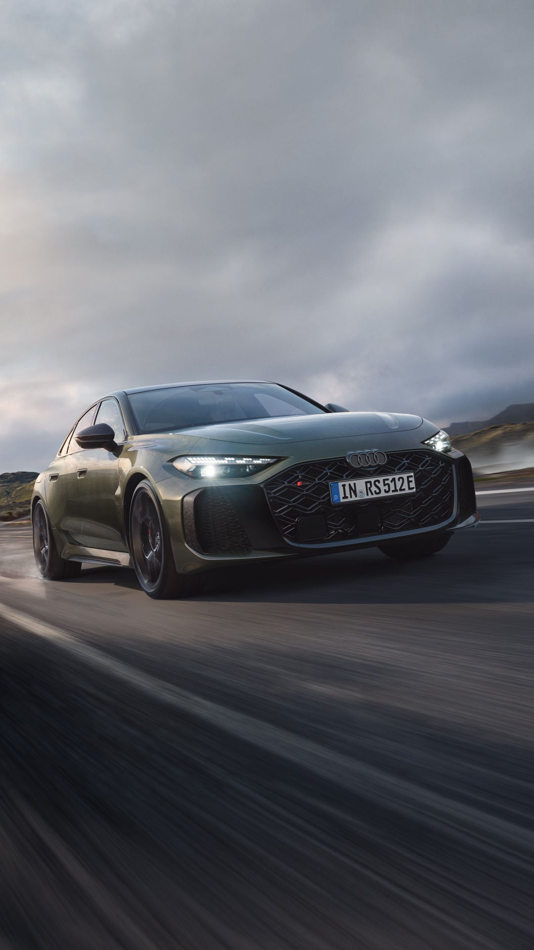 Die RS 5 Limousine schräg von vorn fährt auf einer Gebirgsstraße. Wasserdampf steigt links und rechts auf.